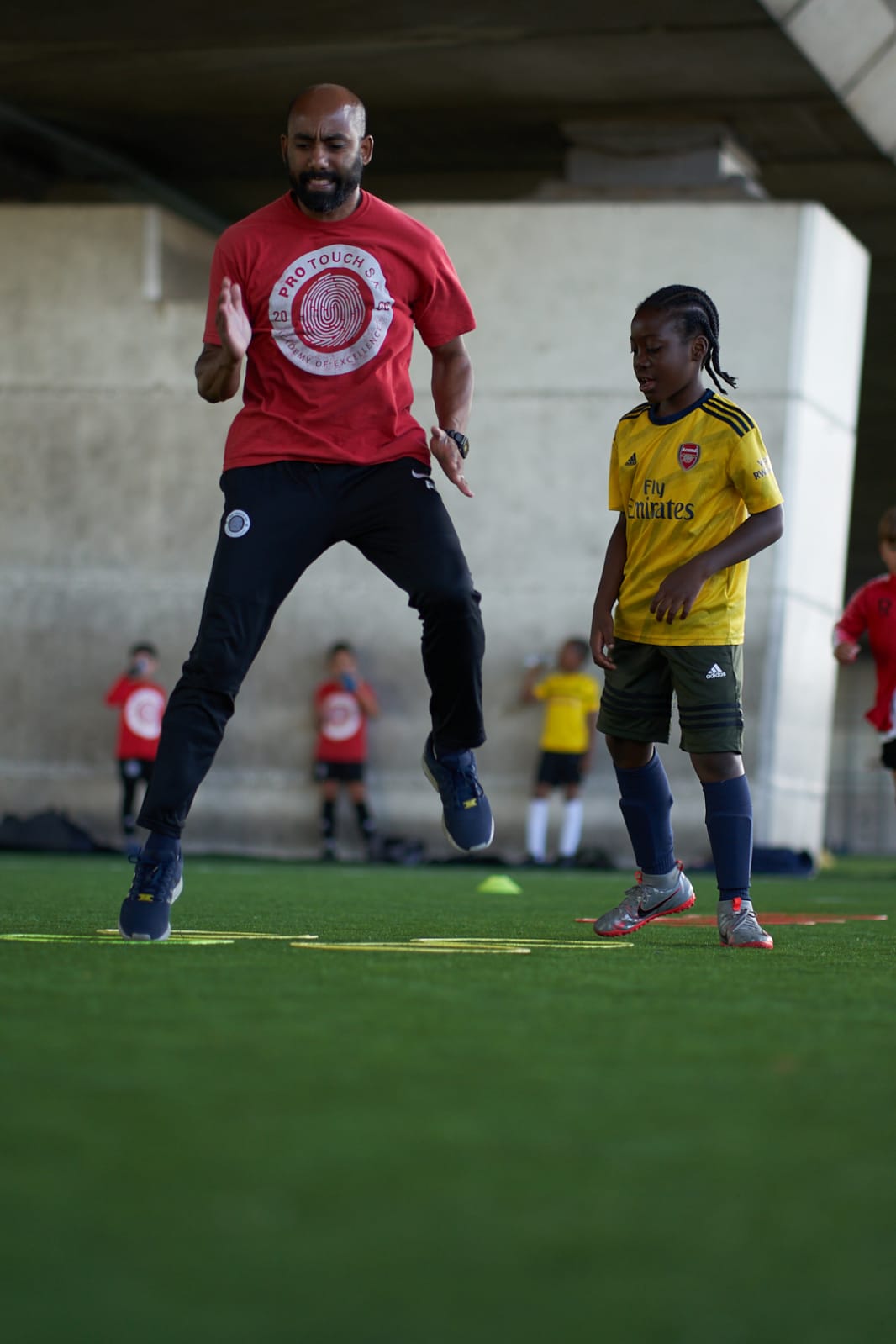 Ash Rahman coaching a young player through a footwork drill